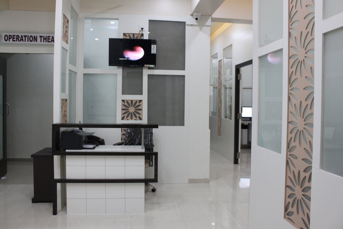 Theatre-side concierge desk at Insight Institute, framed by laser-cut floral panels with an endoscope-view feed playing on the wall monitor above